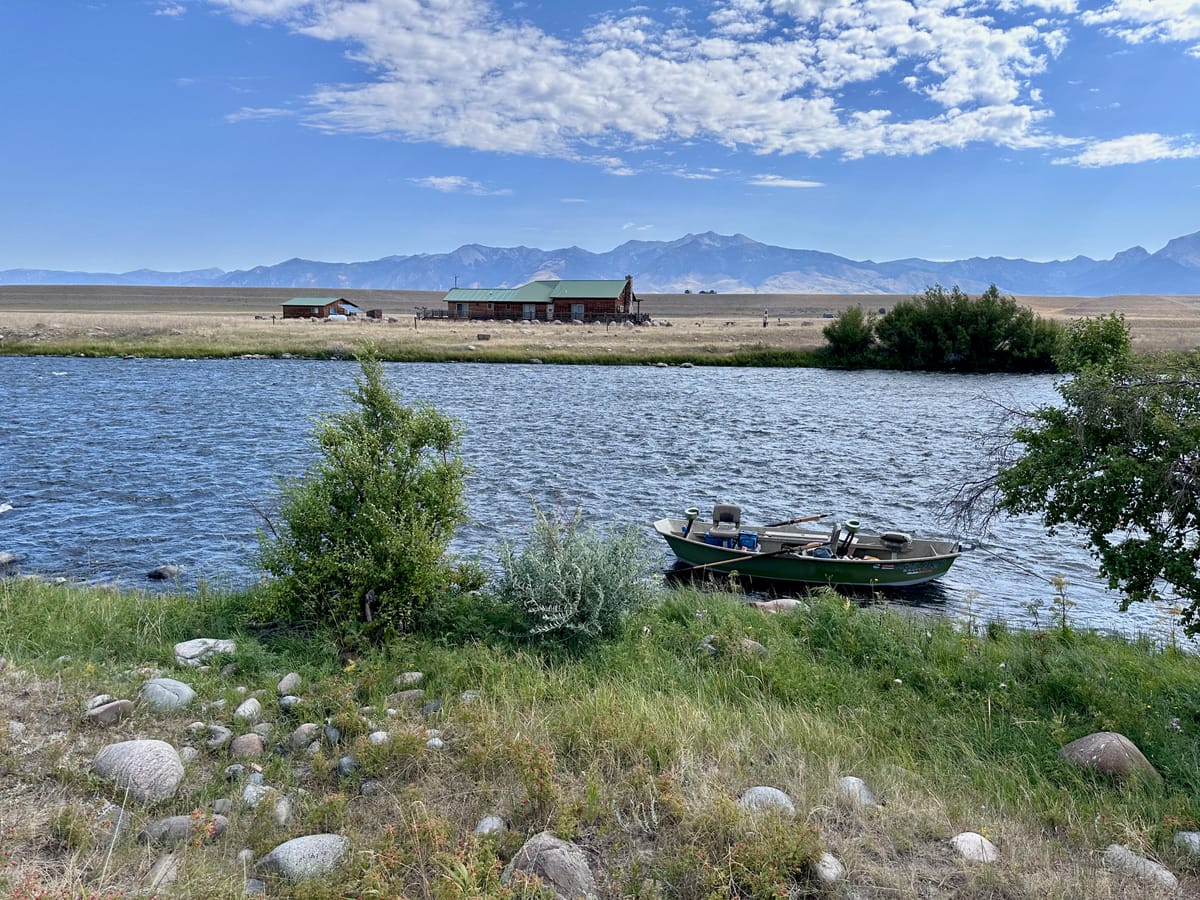 A drift boat floats in the midground, anchored at the side of Montana's Madison river
